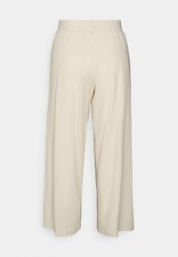 Crème wijde broek met ribbeltextuur en elastische taille. Geen zichtbare zakken; zoom eindigt op enkelhoogte. Minimalistisch ontwerp.