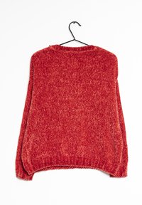 Red knitted sweater with a textured fabric, featuring a rounded neckline and long, loose sleeves, hung on a black hook.
