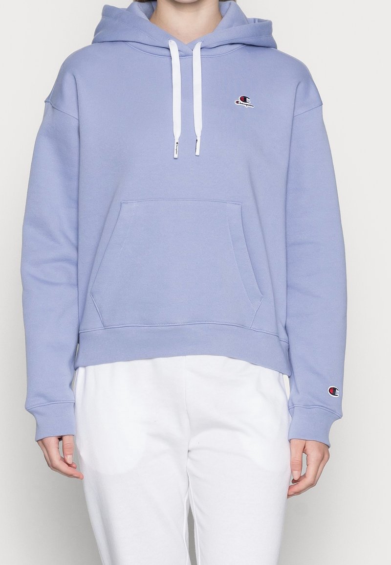 Light purple hoodie made of cotton, featuring a front pocket, drawstrings, and a small logo on the chest and sleeve. Soft texture.