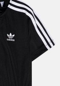 Svartidretts T-skjorte med korte ermer, med hvit tre-stripes design på skuldrene og en liten hvit brodert logo på brystet.