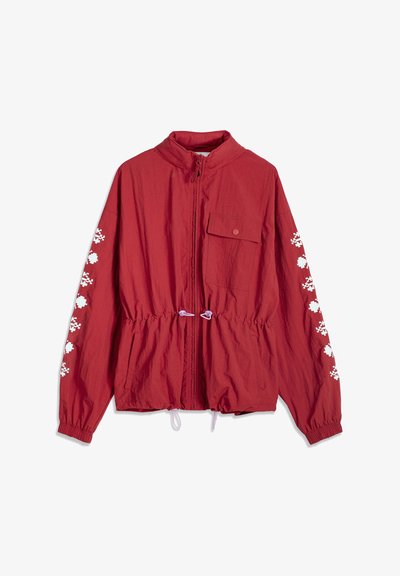 Veste rouge légère avec fermeture éclair frontale, poche poitrine à bouton-pression, poignets élastiques, motif pixellisé blanc sur les manches, et cordons ajustables à la taille.