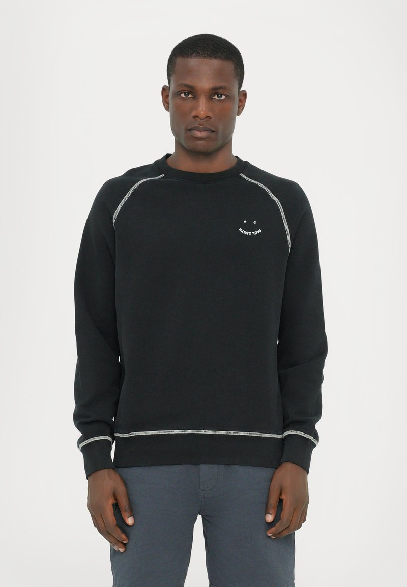 Svart sweatshirt i bomull med rund halsringning, långa ärmar och silverfärgade sömnadsdetaljer. Litet smiley-logotyp på bröstet.