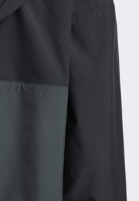 Chaqueta resistente al agua con un diseño bicolor en gris oscuro y negro, con textura suave y un corte inspirado en la utilidad.