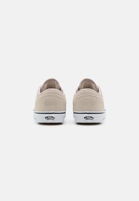 Beige suede sneakers with a low-top design, white rubber soles, and a logo on the heel. Features the numbers "66/99" embossed on the back.