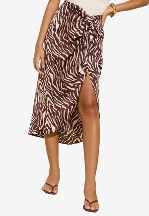 Brown and cream zebra-patterned skirt with a side slit, tied waist detail, and lightweight fabric, featuring a relaxed fit.