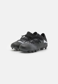 Scarpe da calcio nere realizzate in materiale sintetico texturizzato con un design a bassa taglia, dotate di lacci neri e accenti bianchi del logo.