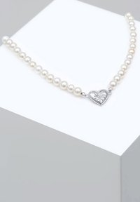 Collana di perle con perle bianche rotonde e una chiusura a forma di cuore in argento con un'incisione floreale dettagliata. Texture liscia e design elegante.
