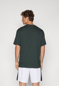 Donkergroene katoenen T-shirt met korte mouwen, ronde hals en een relaxte pasvorm. Heeft vlakke naden en een gladde textuur.
