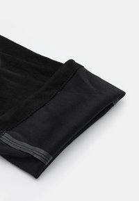 Prenda negra con un tejido suave y texturizado, y una banda elástica lisa y contrastante en el puño. Bordes limpios con detalles de costura.