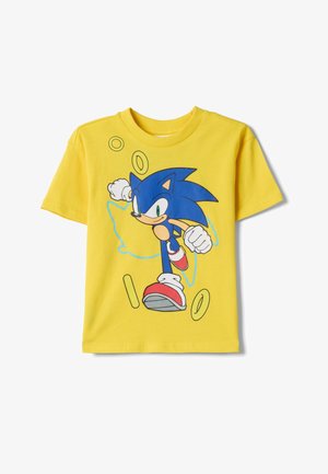 Gelbes Kurzarmhemd mit laufendem, blauem Cartoon-Igel und verstreuten goldenen Ringen auf der Vorderseite.