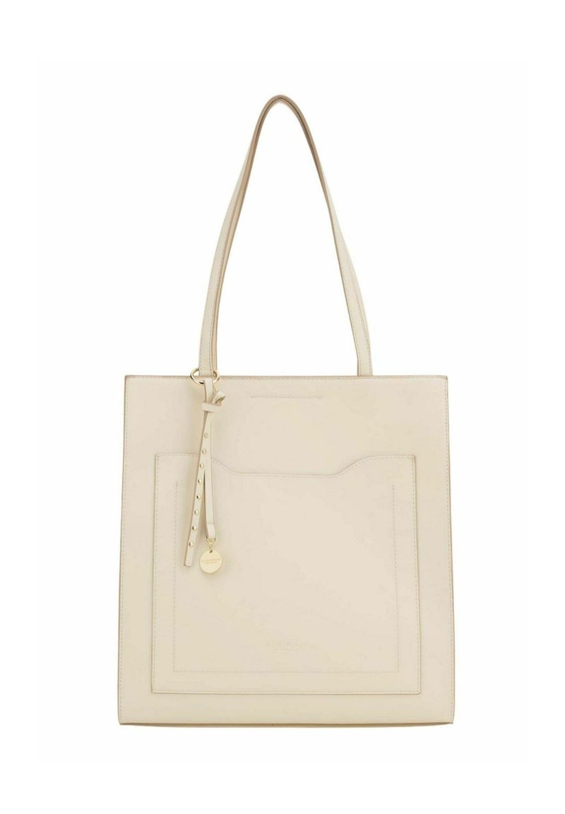 Sac fourre-tout beige clair en cuir avec deux longues anses, une poche avant et un détail de sangle ornée d'un charm rond en or.