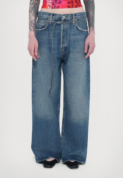 Bredde blå denim jeans med en falmet vask, fem lommer og en knaplukning. Har en flettet snøre detalje i taljen.