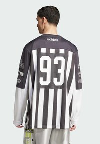 Mustvalge triibuline pikkade varrukate jerser, mille seljal on suur võrgust number "93", kaeluses "adidas" logo ja graafilised detailid varrukatel.