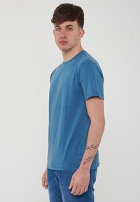 T-shirt blu a maniche corte realizzato in un tessuto morbido e traspirante, con scollatura a girocollo e un piccolo logo sul petto.