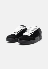 Black suede sneakers with white laces, featuring a textured upper, padded collar, and rubber sole. No prominent branding visible.