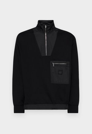 Pullover nero con colletto alto, chiusura con zip e un'apertura a forma di V. Presenta una tasca frontale con zip e un tessuto liscio e texturizzato.