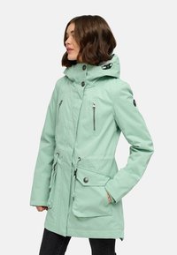 Svetlo mint zelena parka s kapuco, ki ima zadrgo in gumbne zaklope, nastavljiv zavihek in več žepov. Gladek, vodoodporen material.