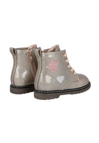Botas plateadas brillantes hasta el tobillo con detalles en forma de estrella y corazón rosas, cordones beige y cremallera lateral. Acabado texturizado y suela de goma.