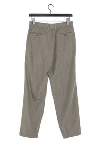 Beige, leichte Hose aus strukturiertem Stoff. Mit zwei Gesäßtaschen mit braunen Knöpfen und geradem Beinabschluss. Hängt an einem schwarzen Haken.
