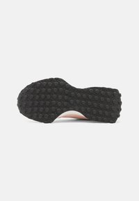 Semelle de chaussure avec un fond en caoutchouc noir texturé, comportant des grips circulaires, une forme courbée et un profil latéral lisse rose.