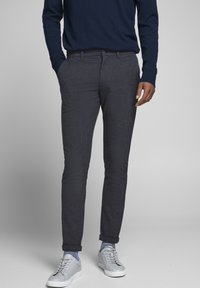 Marineblå teksturerede stretchbukser med slim fit, der har en knaplukning, sidelommer og opbrettede kanter, kombineret med grå sneakers.