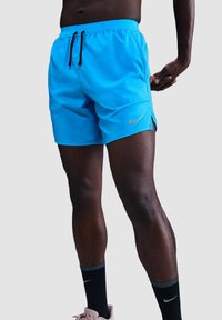 Pantalones cortos deportivos azules con cintura ajustable, bolsillos laterales y logo de Nike en plata. La tela parece ligera con una textura suave.