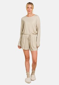 Beige gemusterter Loungeanzug mit einem Langarmoberteil und Shorts mit elastischem Bund und Kordelzug. Weicher Stoff, lockere Passform.