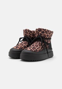 Bottines à imprimé léopard avec un dessus en tissu doux, semelle en caoutchouc noir, bout rond et lacets noirs, avec un design de revers pliable.