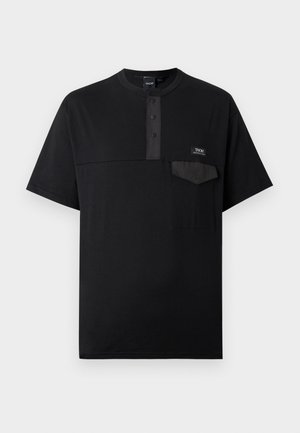 T-shirt noir à manches courtes avec un col rond, une patte de boutonnage à trois boutons, et une petite poche à rabat sur la poitrine gauche avec une étiquette de la marque.