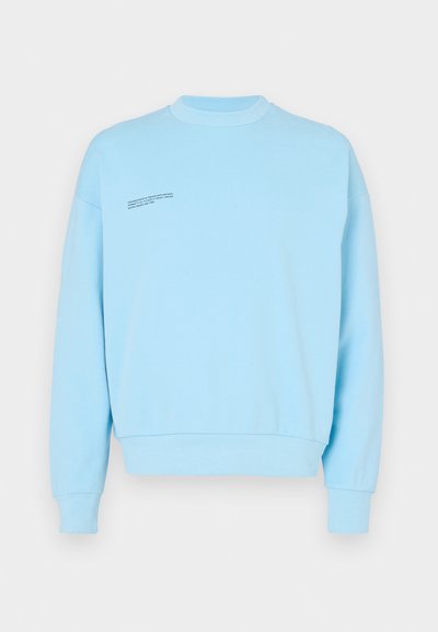 Lyseblå sweatshirt lavet af en blanding af bomuld, med rund hals, lange ærmer og en lille sort tekstdetail på forsiden.