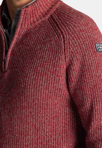 Rood en grijs gebreid trui met een hoge kraag en een design met halve ritssluiting. Kenmerkt zich door een textuurpatroon en een klein merklabel op de schouder.