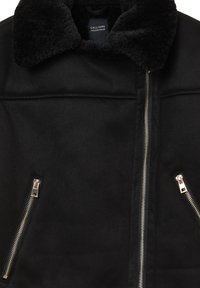 Giacca in finta suede nera con colletto fluffy nero, dotata di due tasche con zip e chiusura centrale con zip. Finitura texture e liscia.