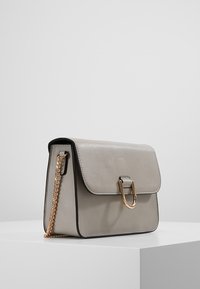 Szara skórzana torebka z klapką, złotymi elementami i łańcuszkowym paskiem. Charakteryzuje się prostokątnym kształtem i gładką fakturą.