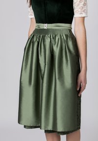 Grüne Satinrock mit elastischem Bund, versehen mit einem metallischen Verschluss. Das Design umfasst texturierte Spitze in einem dunkleren Grün an der Seite.