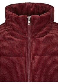 Burgunder kordfløyel zip-up fleece med høy krage. Har ribbet tekstur og en sølvfarget metallglidelås, som gir varme og komfort.