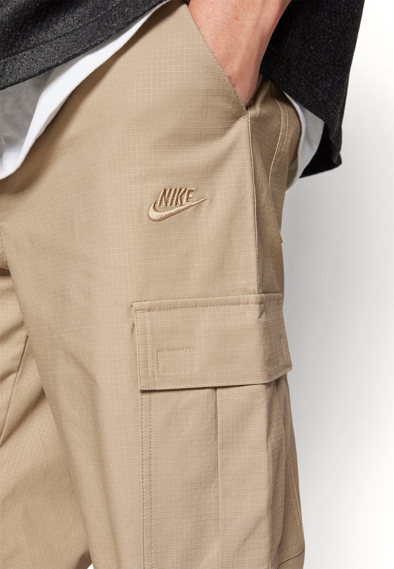 Pantalons cargo beiges en tissu texturé. Dotés de poches latérales, d'un motif en quadrillage subtil et d'un logo Nike brodé de couleur assortie.