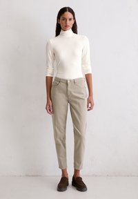 Light beige turtleneck top and light gray slim-fit pants. Material appears soft with a smooth texture. Brown slip-on shoes complete the outfit.