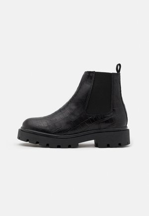 Bottines Chelsea noires en cuir texturé avec motif crocodile, dotées de panneaux élastiques et d'une semelle épaisse. Onglet à l'arrière pour un enfilage facile.