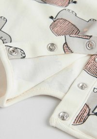 Prenda de algodón blanca con ilustraciones de hipopótamos en gris y rosa, con cierres a presión en la parte inferior y una textura suave.
