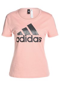 Jasnoróżowa bawełniana koszulka z czarnym logo Adidas z pogrubionym napisem i wzorem graficznym, okrągłym dekoltem i krótkimi rękawami.