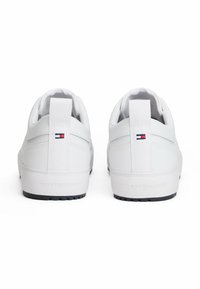 Weiße Sneaker mit glattem Lederfinish, einem Logo-Akzent, gepolstertem Absatz und schwarzer Gummisohle für besseren Halt.