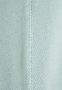 Närbild av ljusblått stickat tyg som visar detaljerad vertikal sömnad i mitten.