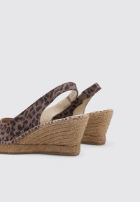 Sandalias de cuña con estampado de leopardo, suela de yute, diseño de tipo slingback y tela texturizada. Presentan un tacón curvado para mayor soporte y comodidad.