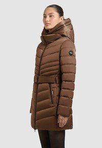 Braune Puffjacke mit hohem Kragen und Kapuze, gestepptem Muster, taillierter Taille und seitlichen Reißverschlusstaschen. Mit Logo am linken Ärmel.