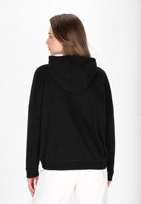 Schwarzer Kapuzenpullover mit lockerer Passform, weichem Material und gerippten Bündchen. Die Rückseite zeigt ein einfaches, schmuckloses Design.