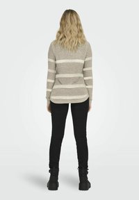 Pull rayé gris et crème avec un ourlet rond, des manches longues et un tricot texturé. Associé à un jean skinny noir et des bottes noires chunky.
