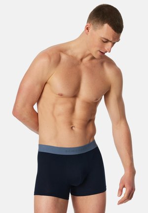 Mörkblå boxershorts med ett ljust grått elastiskt midjeband, med märkesnamnet "SCHIESSER" präglat på framsidan av bandet.
