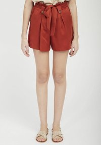 Rostfärgade högmidjade shorts med en knytbälte, två framfickor och knapppdekorationer, tillverkade av lättviktsmaterial.