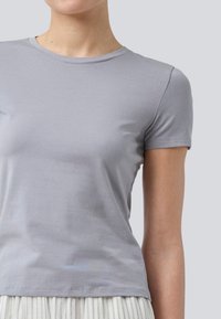 Grå bomulds t-shirt med korte ærmer, rund halsudskæring og tætsiddende design. Glat tekstur med minimale syninger.