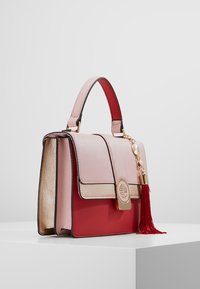 Kompaktowa torebka z różowej i czerwonej skóry, z złotym okuciem oraz bocznym chwostem. Posiada zapięcie na klapę i usztywnioną konstrukcję.